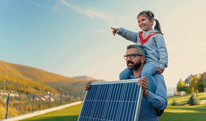Mężczyzna z córką na grzbiecie, trzymający panel PV