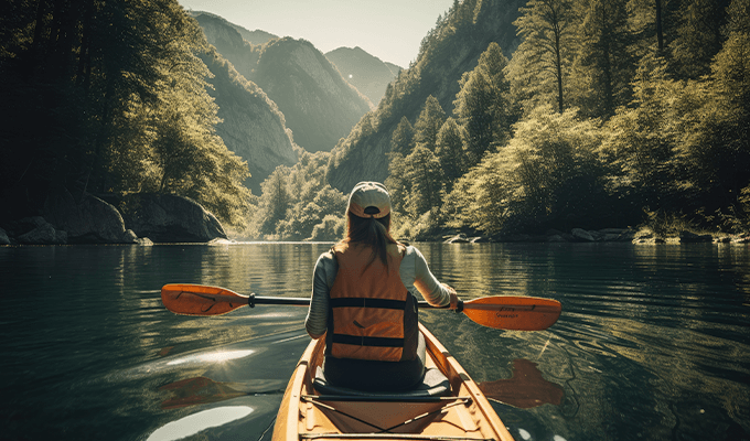 Kobieta pływająca na kajaku w górskiej dolinie