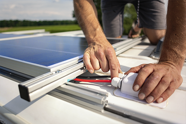 zbliżony kadr na ręce specjelisty który montuje panel fotowoltaiczny na dachu