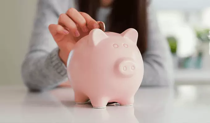 kobieta wrzucająca monetę do świnki skarbonki